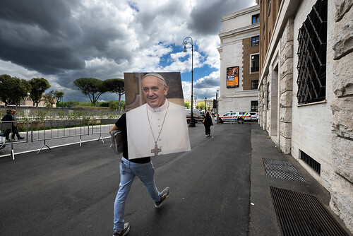 Mann trägt Portrait von Papst Franziskus durch die Straßen Roms.